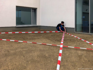 Un étudiant place du ruban en plastique sur une plantation de gazon