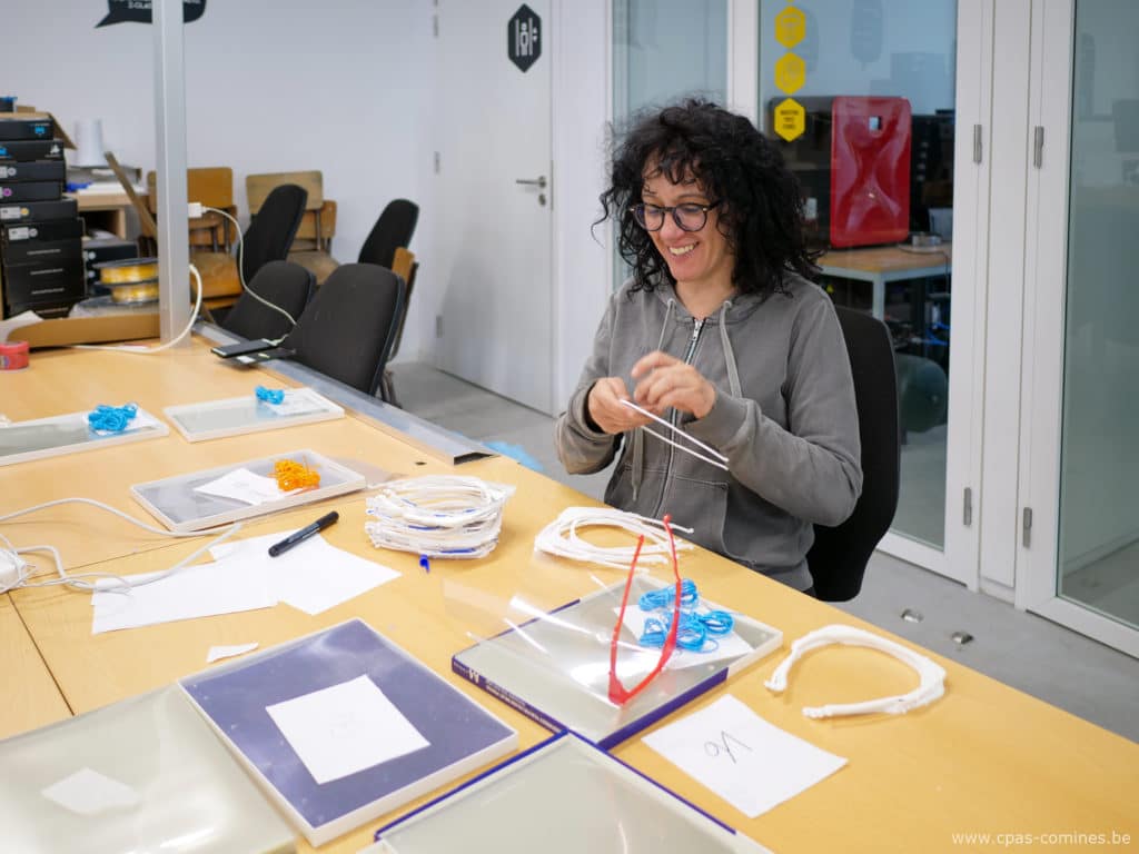 Une dame souriante réalise des visières en plexiglas